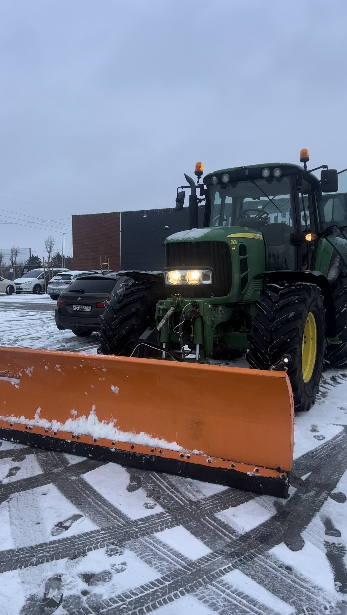 Traktor Elektro-Bud podczas odśnieżania parkingu przed galerią handlową